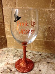 a wine glass that says drink up witches on the bottom and an orange glitter base