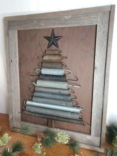 a christmas tree made out of old tin cans is displayed in a frame on a table