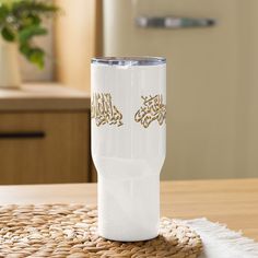 a white coffee cup sitting on top of a wooden table next to a wicker place mat