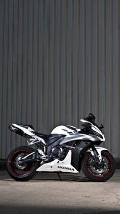 a black and white motorcycle parked in front of a building with red rims on it