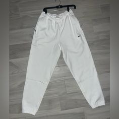 Elevate Your Activewear Game With These Nike Sportswear Solo Swoosh Fleece White Sweatpants For Men. The Cozy Fleece Fabric Will Keep You Warm During Your Workouts, While The Stylish Design Makes Them Perfect For Casual Wear Too. The Nike Brand Name Speaks For Itself In Terms Of Quality, And The Sweatpants Come In Size S, Perfect For A Regular Fit On Men. These Sweatpants Are Ideal For Any Occasion, Whether It Be A Morning Jog Or A Casual Day Out. The White Color And Swoosh Logo On The Side Give Nike Sports Sweats With Pockets, Nike Sweats With Pockets For Sports, Sporty Sweats With Pockets For Sports, White Joggers With Ribbed Waistband For Sports, White Sweatpants With Ribbed Waistband For Sports, White Athleisure Tracksuit For Gym, Nike Sports Sweats With Elastic Waistband, White Moisture-wicking Tracksuit For Gym, White Moisture-wicking Casual Tracksuit