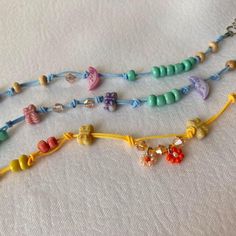 three necklaces with beads and charms on a white tablecloth, one is multicolored