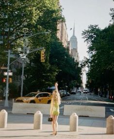 a woman standing on the side of a road pointing up at something in the air