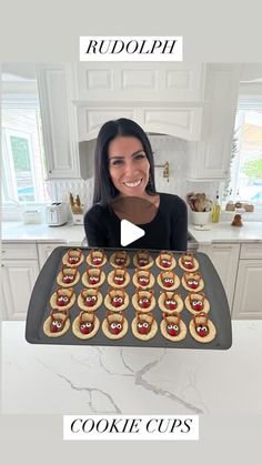 a woman is holding up a cookie tray with cookies on it and the words rudolphpi above her