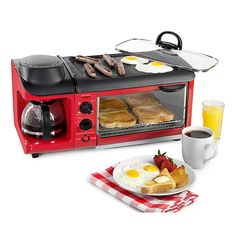 a red toaster oven sitting on top of a counter next to eggs and sausages