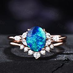 a blue opal and diamond ring on top of a black surface with white diamonds