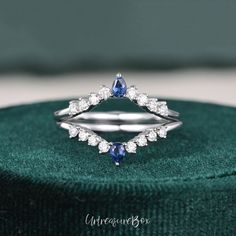 a diamond and sapphire ring sitting on top of a green velvet box