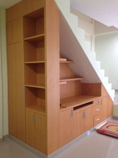 an empty room with some shelves under the stairs