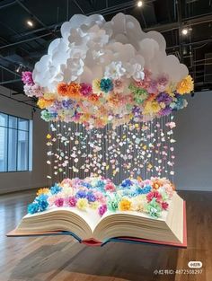 an open book sitting on top of a wooden floor covered in paper flowers and butterflies