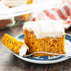 a piece of carrot cake with white frosting on a plate next to a fork