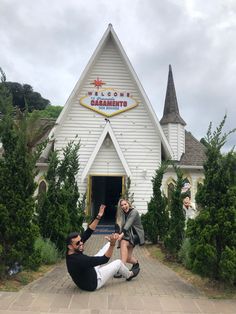 two people sitting on the ground in front of a church