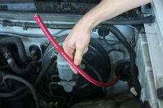 a man is working on an engine in his car with the hose connected to it