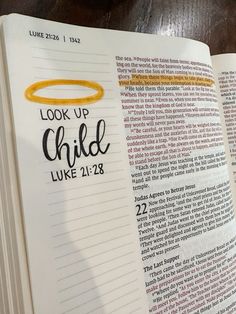 an open bible with the words look up child luke 21 28 written in yellow on it