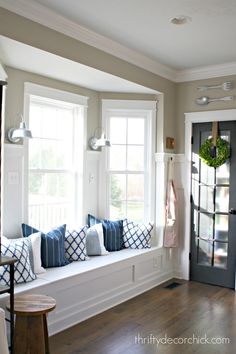 a window seat with blue and white pillows on it in front of a black door