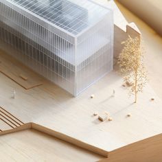 a model of a building on top of a wooden table next to a small tree