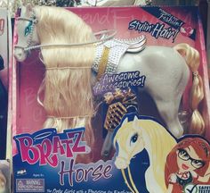 the toy horse has blonde hair and is in its box with other toys around it