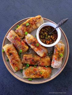 rice paper dumplings on a plate with dipping sauce and green onion garnish