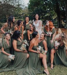 a group of bridesmaids in green dresses posing for a photo with each other