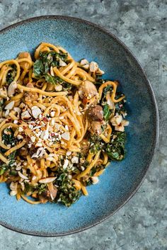 a blue bowl filled with noodles and vegetables