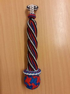 a red, white and blue rope on top of a wooden table next to a vase