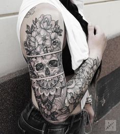 a woman with a skull and flowers tattoo on her arm