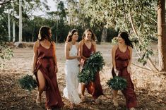 four bridesmaids laughing together in the woods with greenery wreaths on their heads