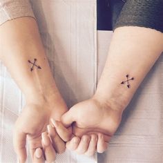 two people holding hands with cross tattoos on them