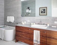 a bathroom with two sinks, a bathtub and a large mirror on the wall