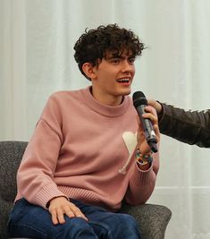 two people sitting down and one is holding a microphone