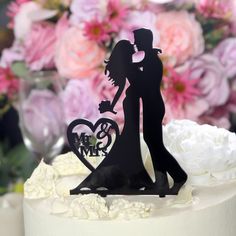 a wedding cake topper with a bride and groom holding a heart shaped cutout