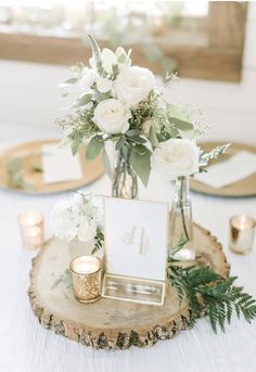 a centerpiece with white flowers and greenery is displayed on a wooden slice at the head table