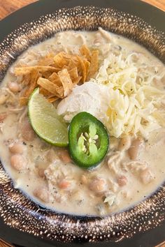 a black plate topped with beans, cheese and guacamole next to tortilla chips