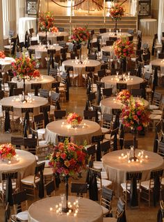 tables and chairs are set up in the center of a hall with floral centerpieces