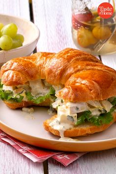 a croissant sandwich on a plate with grapes