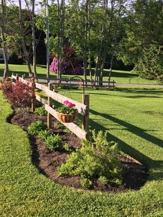 a wooden fence in the middle of a grassy area with flowers growing on top of it