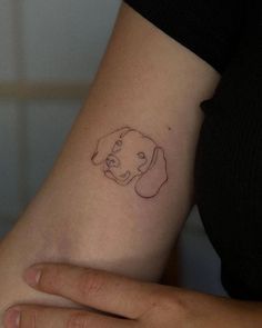 a woman's arm with a small tattoo of a dog on the left side of her arm