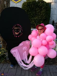 a woman dressed in pink and black with balloons on her head is holding a bunch of pink balls