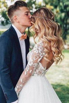 a bride and groom kissing in the park