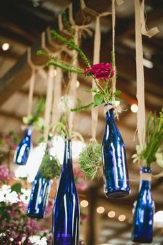 several blue vases with flowers hanging from them