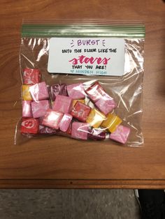 a bag filled with candy sitting on top of a wooden table next to a sign