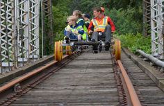 three people in yellow vests are on a train track with one person in a wheel chair