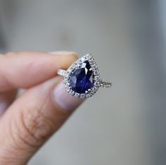 a close up of a person holding a ring with a blue stone in the middle