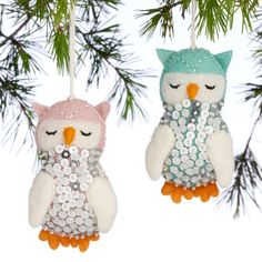 two stuffed owls are hanging from a christmas tree ornament, with sequins on them