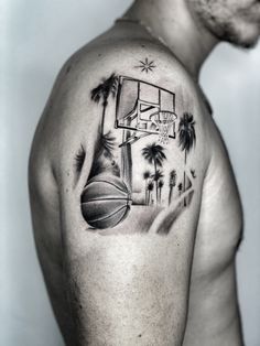 a man with a basketball and palm trees tattoo on his arm, holding a basketball hoop