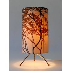 a lamp that is sitting on top of a tripod base with a tree design on it