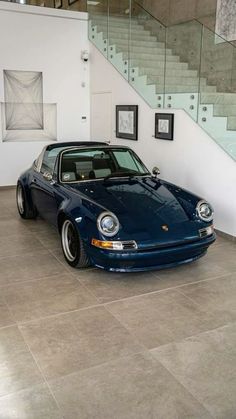 a blue sports car parked in front of a stair case with pictures on the wall