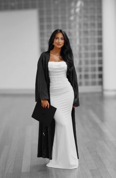 a woman in a white dress and black cardigan standing on a hard wood floor