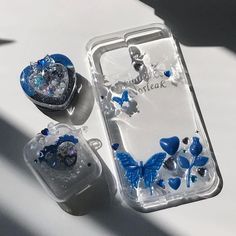 two cases with blue butterflies on them and one has a heart in the middle, while the other is clear