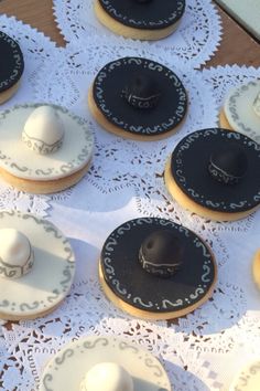 some cookies with hats on them are sitting on a doily covered tablecloth,