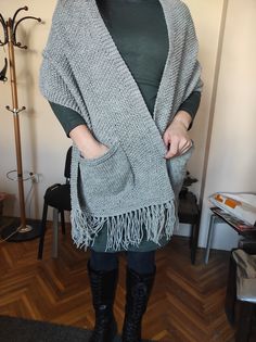 a woman standing in a room wearing a gray shawl